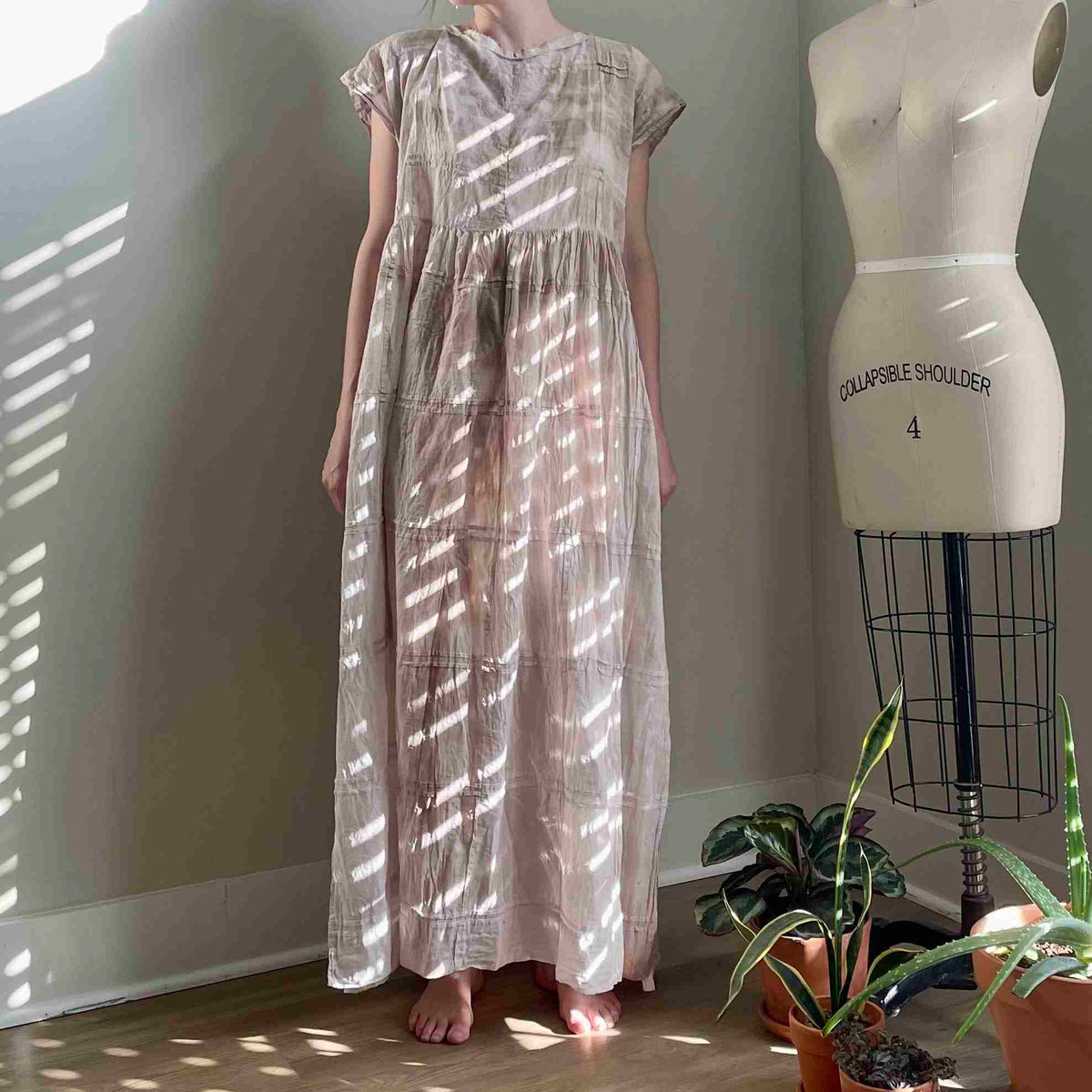 a woman standing next to a dress on a mannequin.