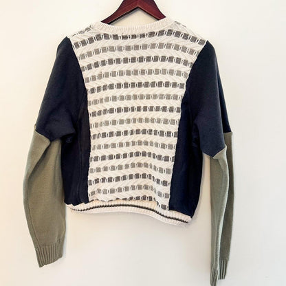 A Neutral Duck & Carhartt Grandpa Sweater Rework hanging on a hanger on a wall.