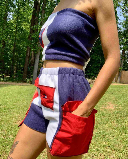 a woman standing in a field with her hands in her pockets.