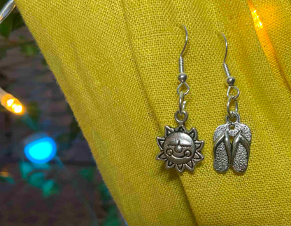 a pair of silver sandals hanging from a pair of earrings.
