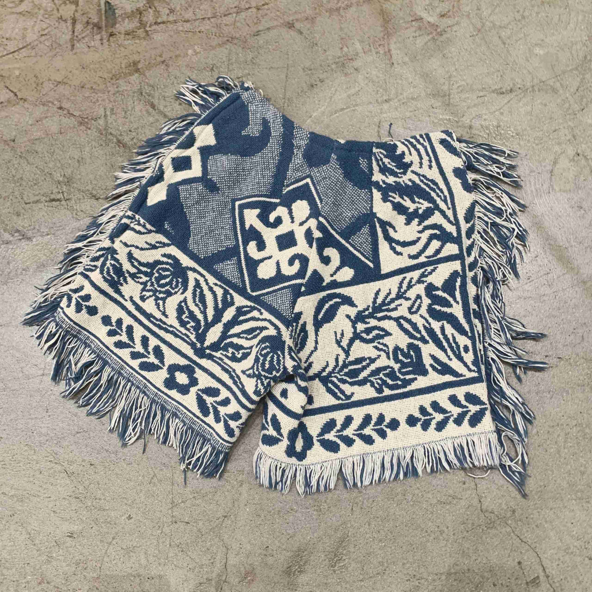 a blue and white blanket laying on top of a sandy beach.