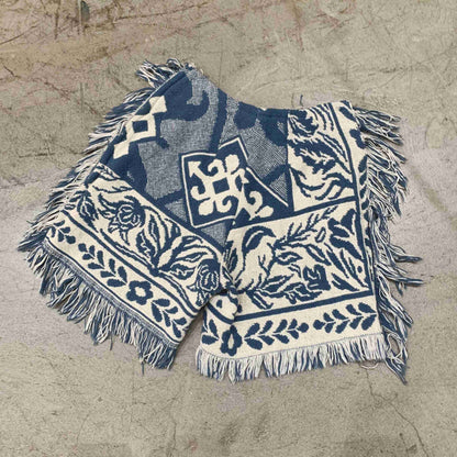 a blue and white blanket laying on top of a sandy beach.