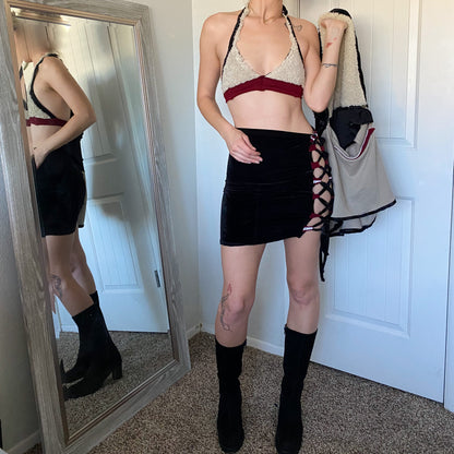 A woman is standing in front of a mirror wearing a bra and skirt.