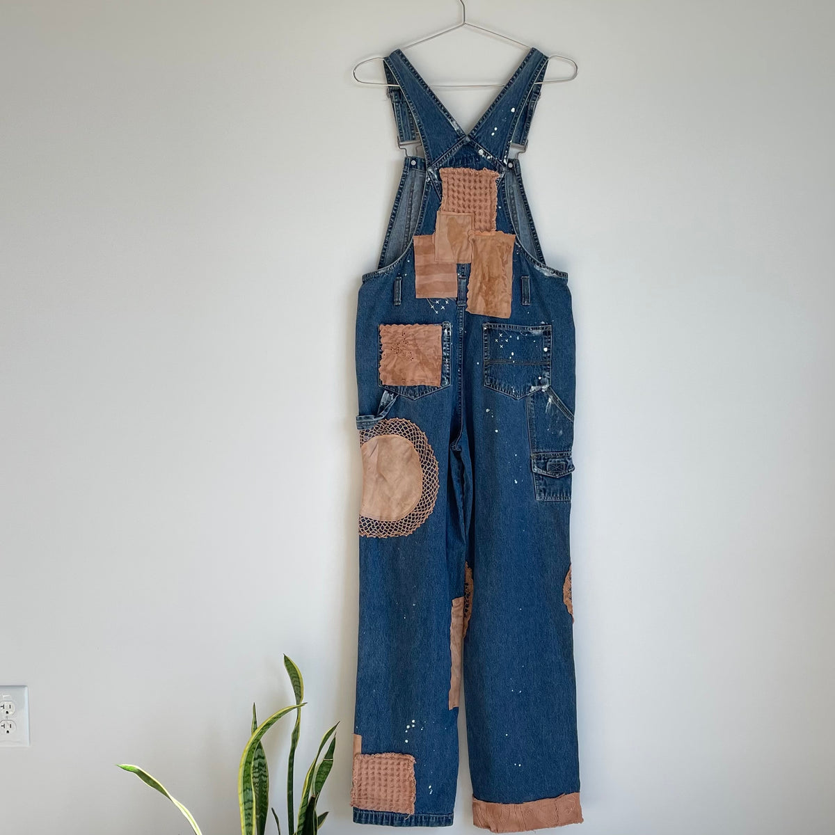 A pair of denim overalls hanging on a wall.