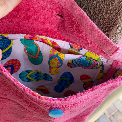 A person is holding a 1of1 pink terrycloth purse with a pair of scissors in it.