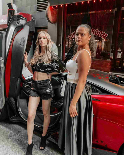two women are standing next to a car.