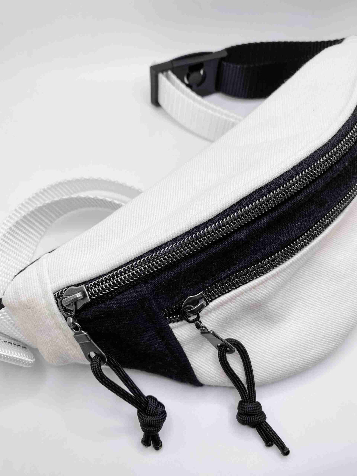 a white and black fanny bag with zippers.