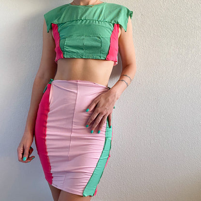A woman wearing a 1of1 mint pink berry crop top and skirt set.