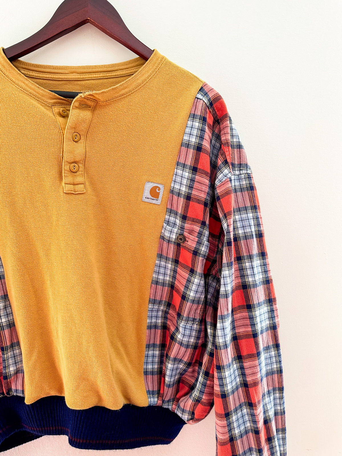 A yellow and blue plaid shirt hanging on a hanger.