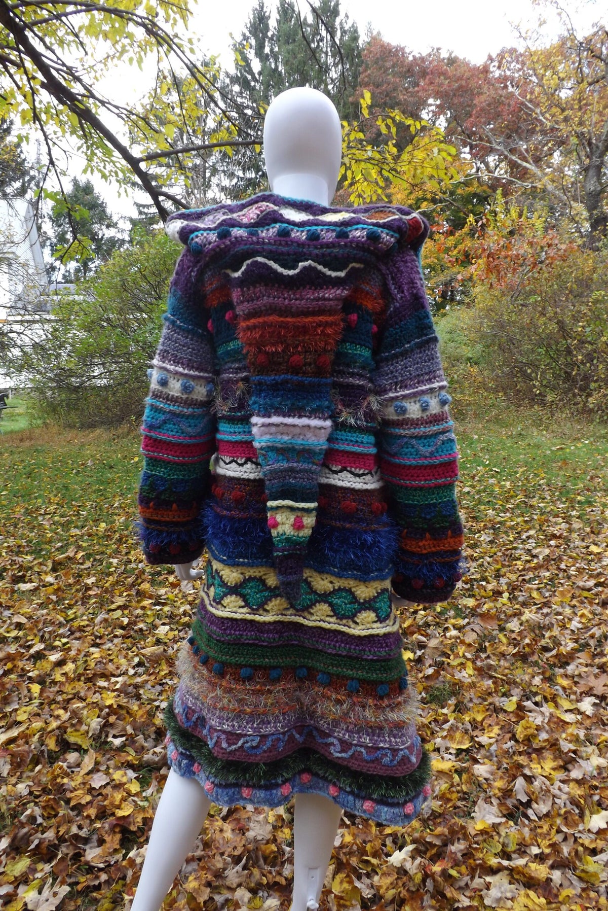 A mannequin wearing a colorful crochet coat.