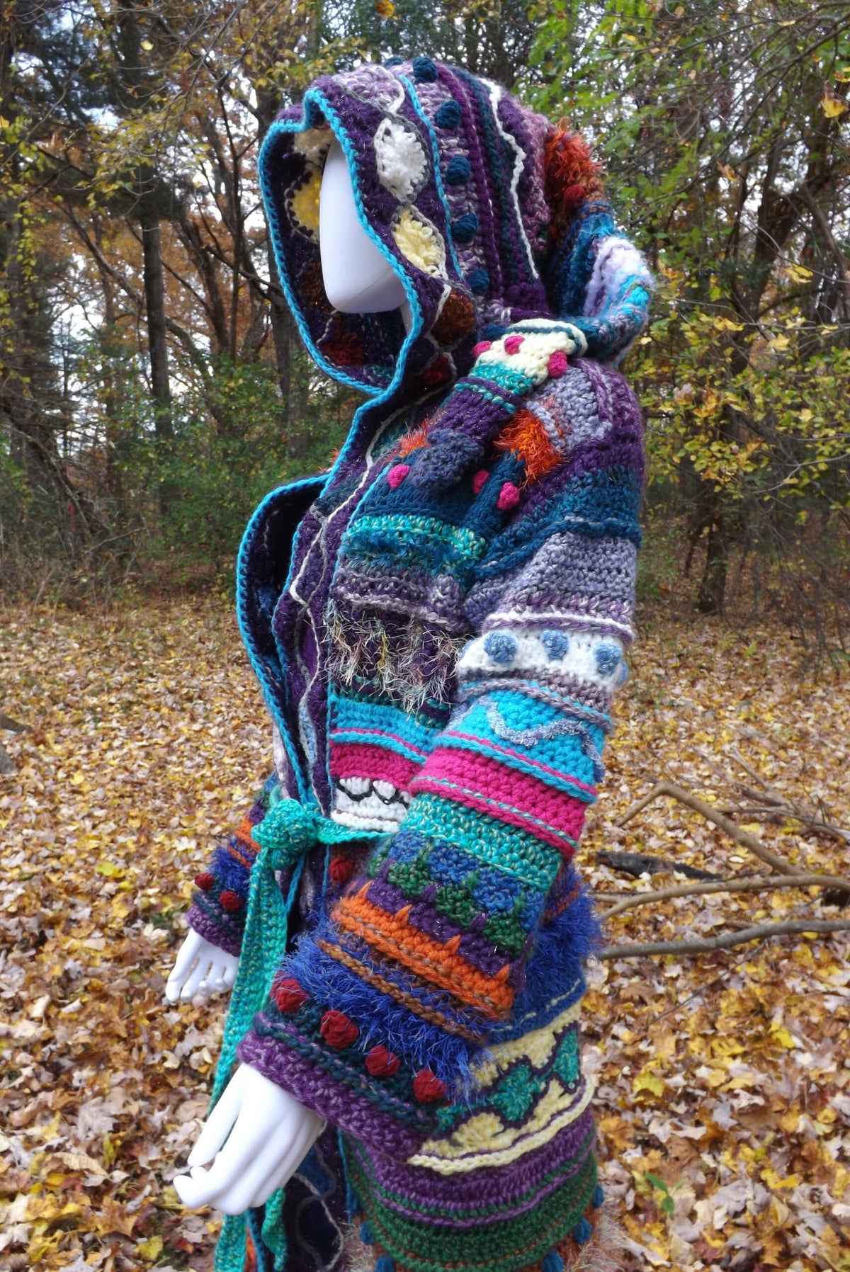 A colorful, one of a kind, crochet coat with long elf hood on a mannequin