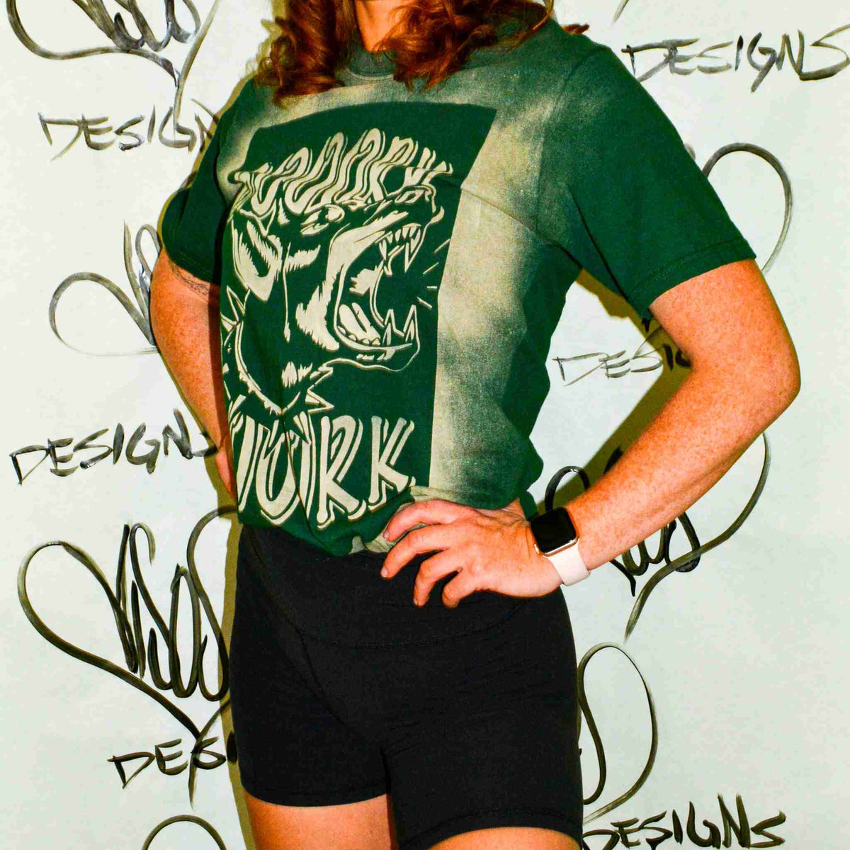 a woman wearing a green shirt and black shorts.