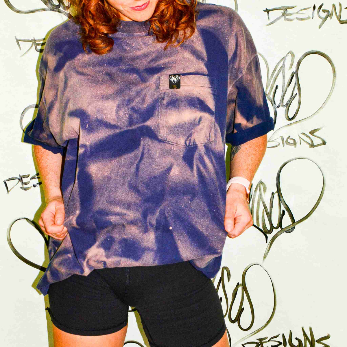 a woman with red hair wearing a purple shirt and black shorts.