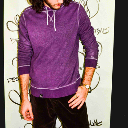 a man with long hair wearing a purple shirt.