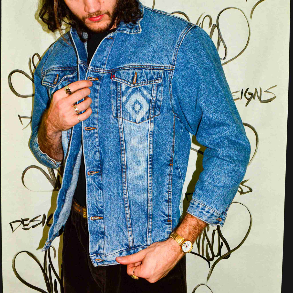 a man with long hair wearing a jean jacket.