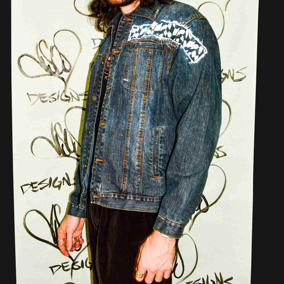 a man with long hair wearing a jean jacket.