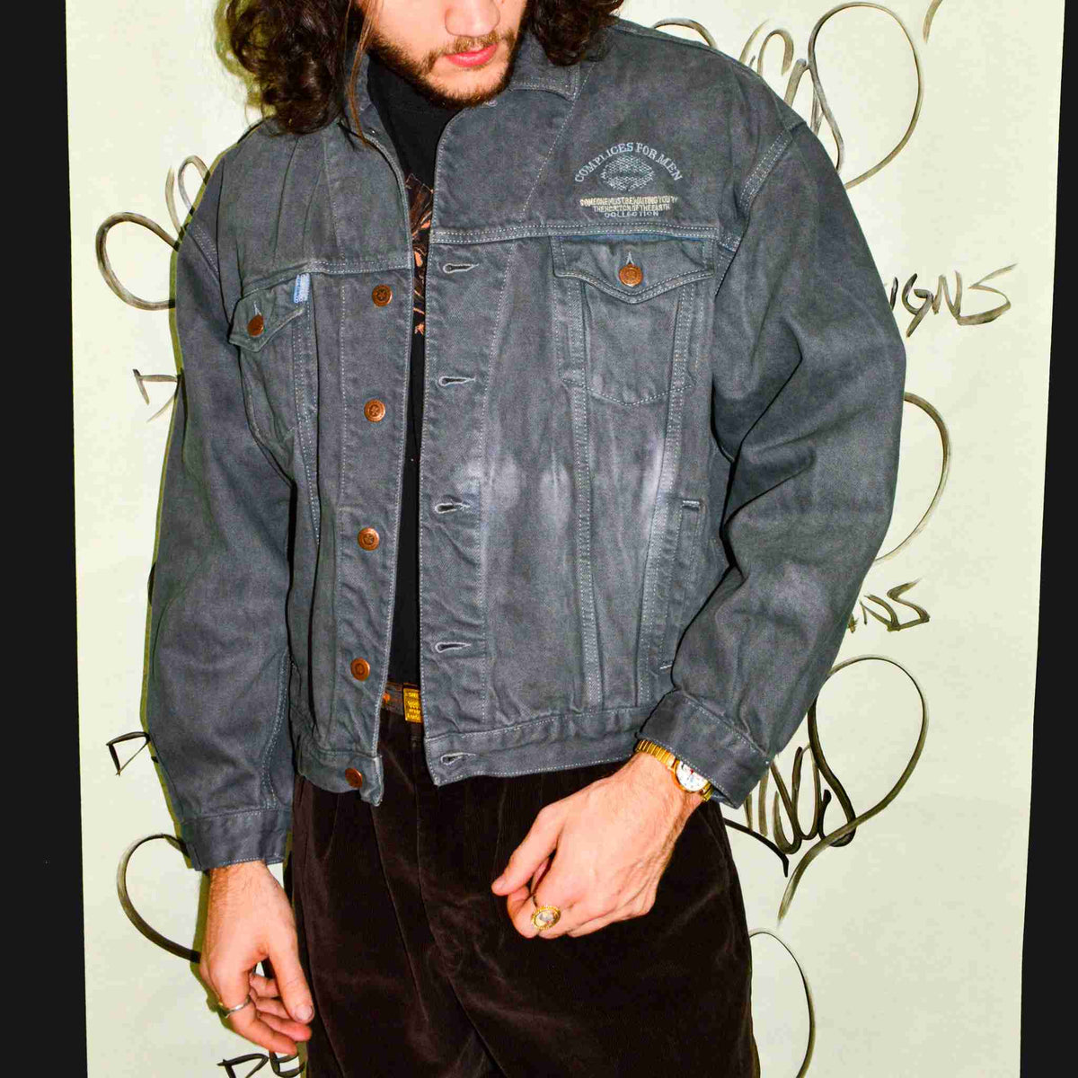 a man with long hair wearing a denim jacket.