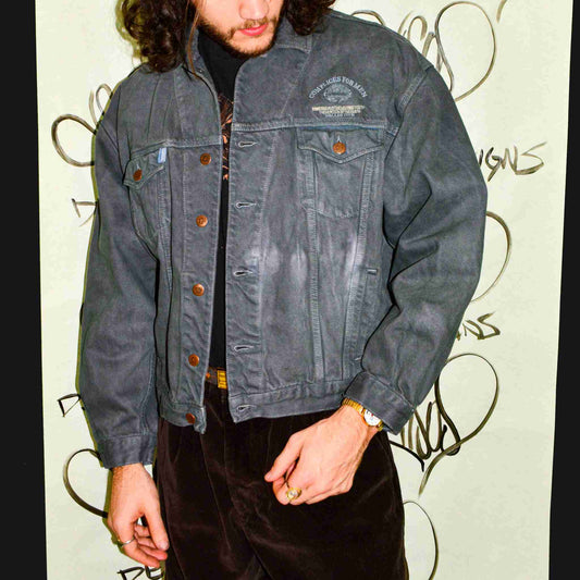 a man with long hair wearing a denim jacket.