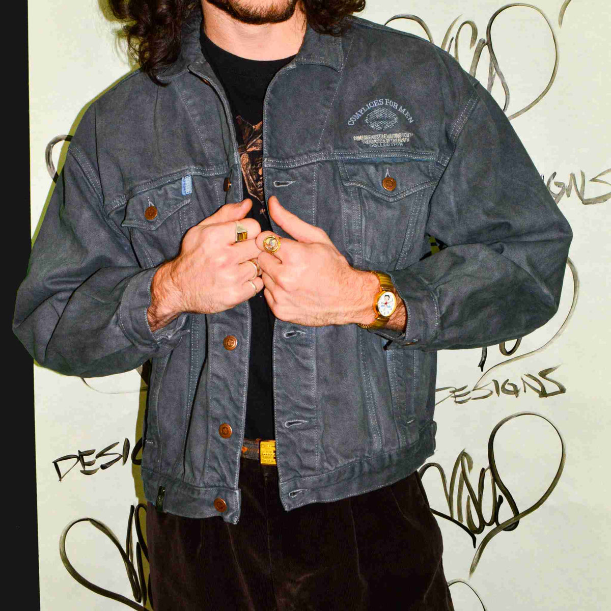 a man with long hair wearing a denim jacket.