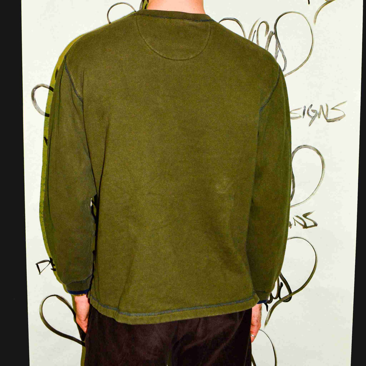 a man standing in front of a wall with graffiti on it.