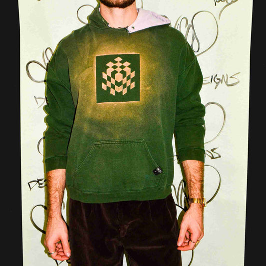 a man in a green hoodie standing in front of a wall.