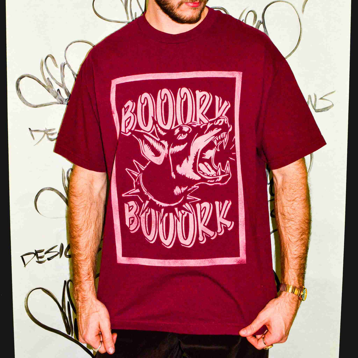 a man standing in front of a wall with a book book t - shirt on.