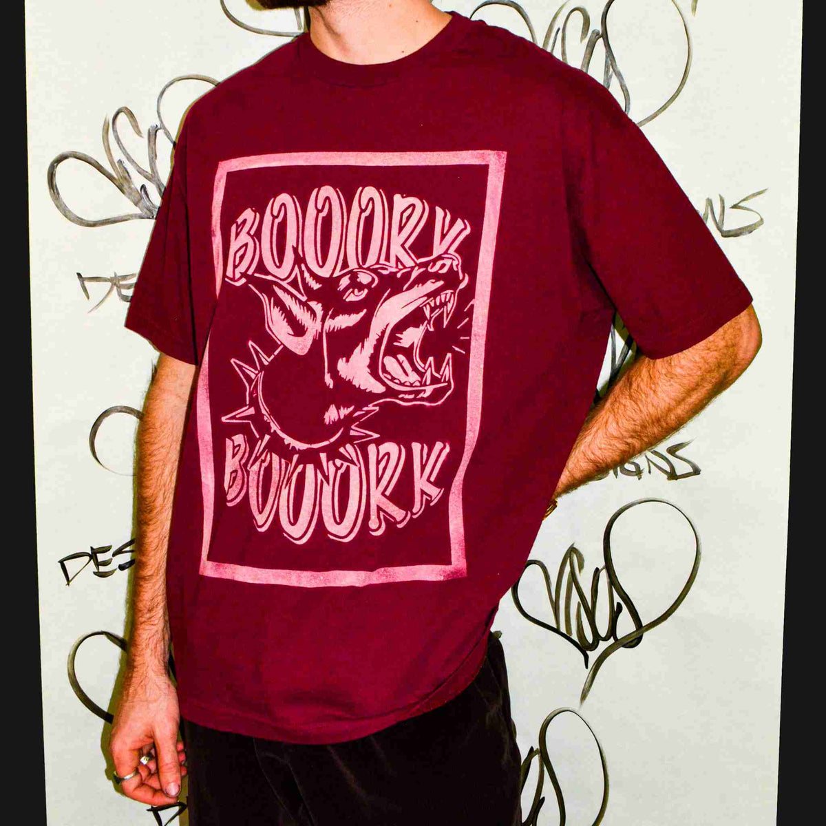 a man standing in front of a wall covered in graffiti.