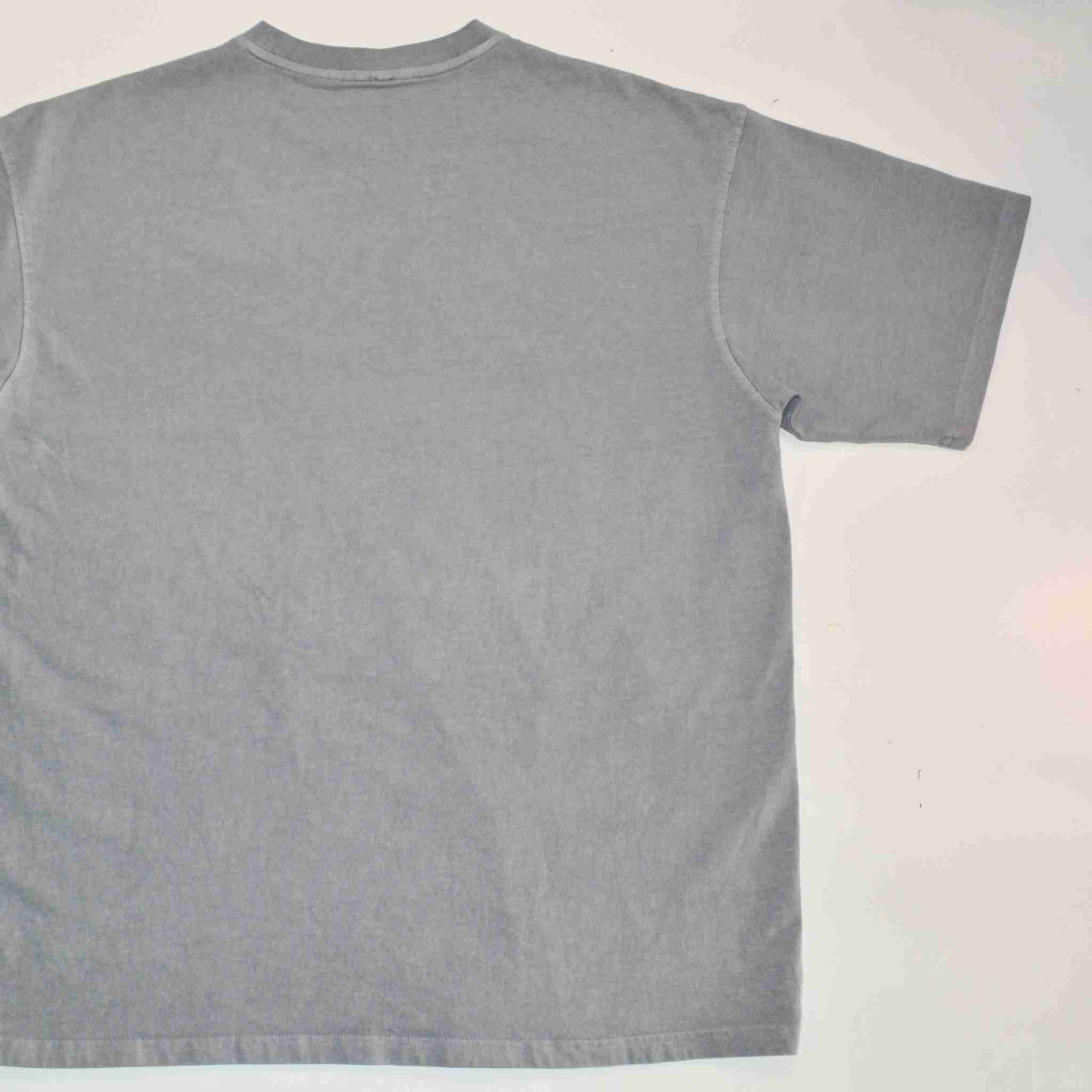 a gray t - shirt is laying on a white surface.