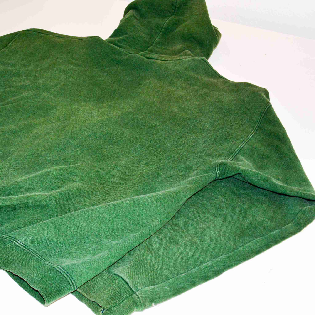 a green t - shirt laying on a white surface.