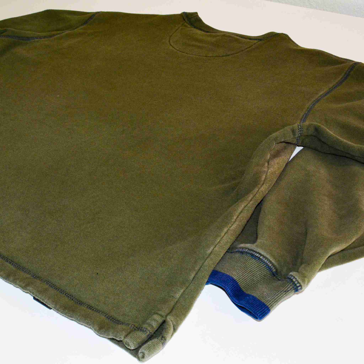 a green shirt laying on top of a white table.