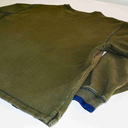 a green shirt laying on top of a white table.
