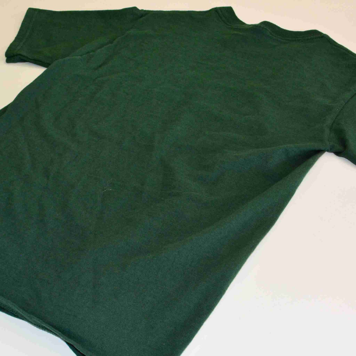 a green t - shirt laying on a white surface.