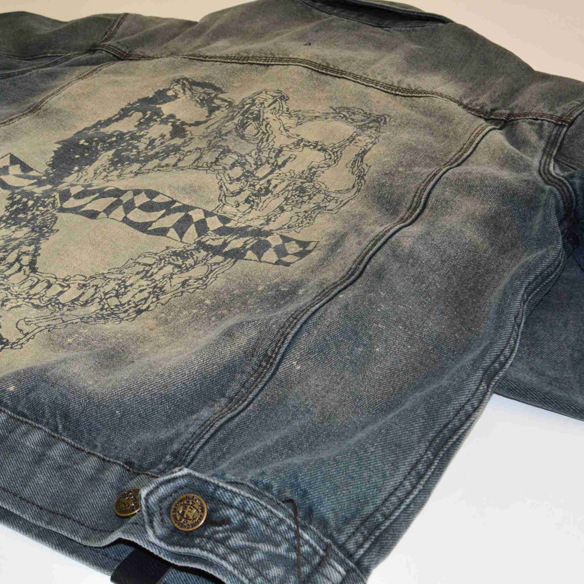 a worn jean jacket with a design on it.