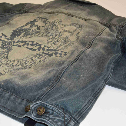 a worn jean jacket with a design on it.