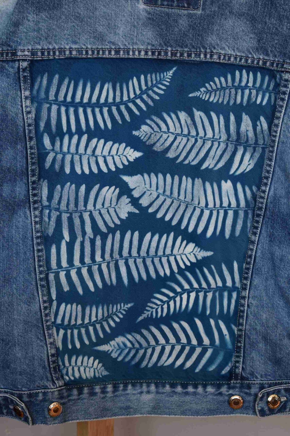 a denim jacket with a fern print on it.