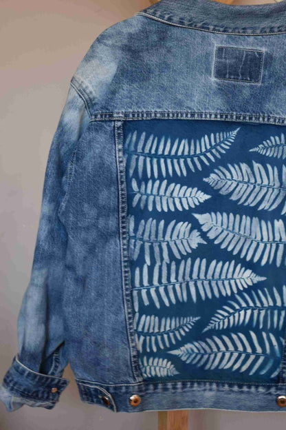 a blue jean jacket with white leaves on it.