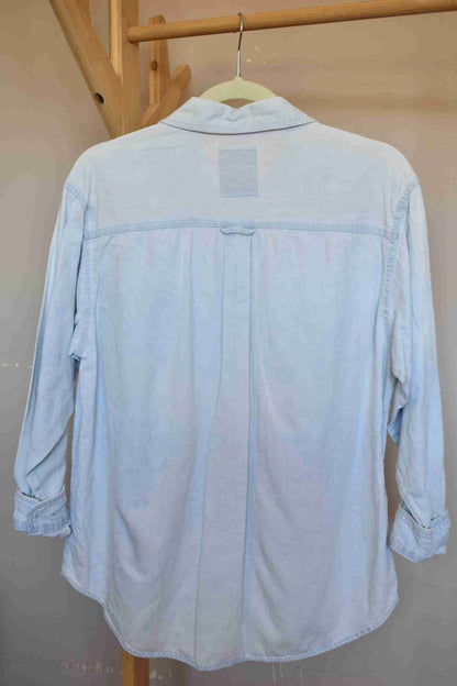 a light blue shirt hanging on a wooden rail.