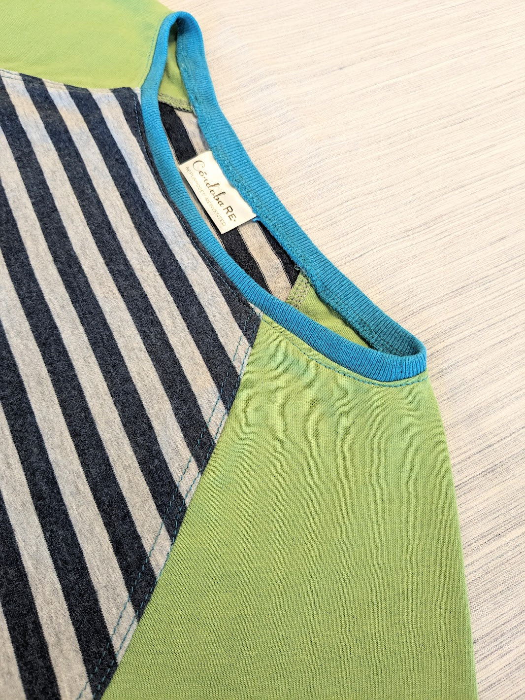 A close up of a green and blue striped t - shirt.