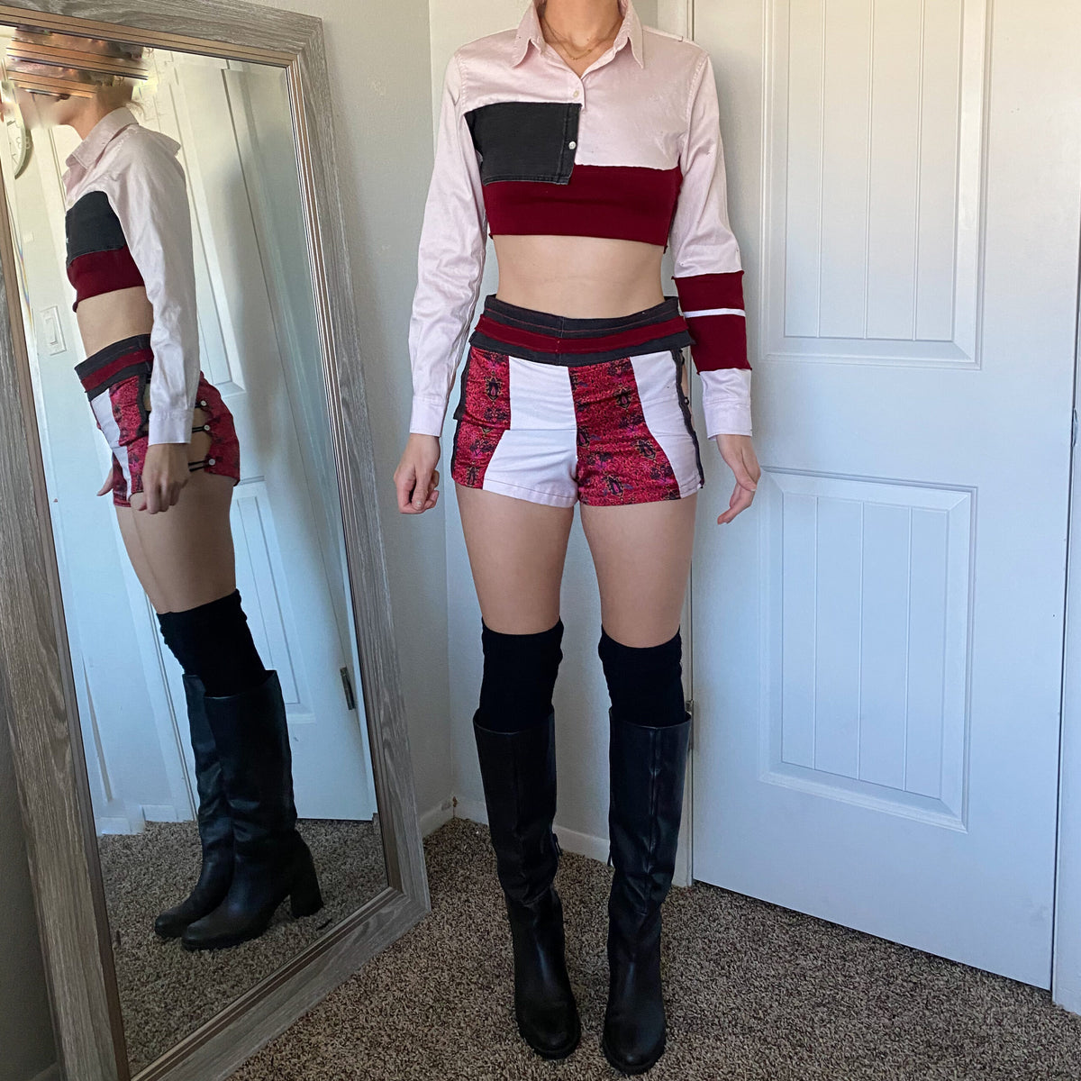 A woman standing in front of a mirror wearing a crop top and thigh high boots.