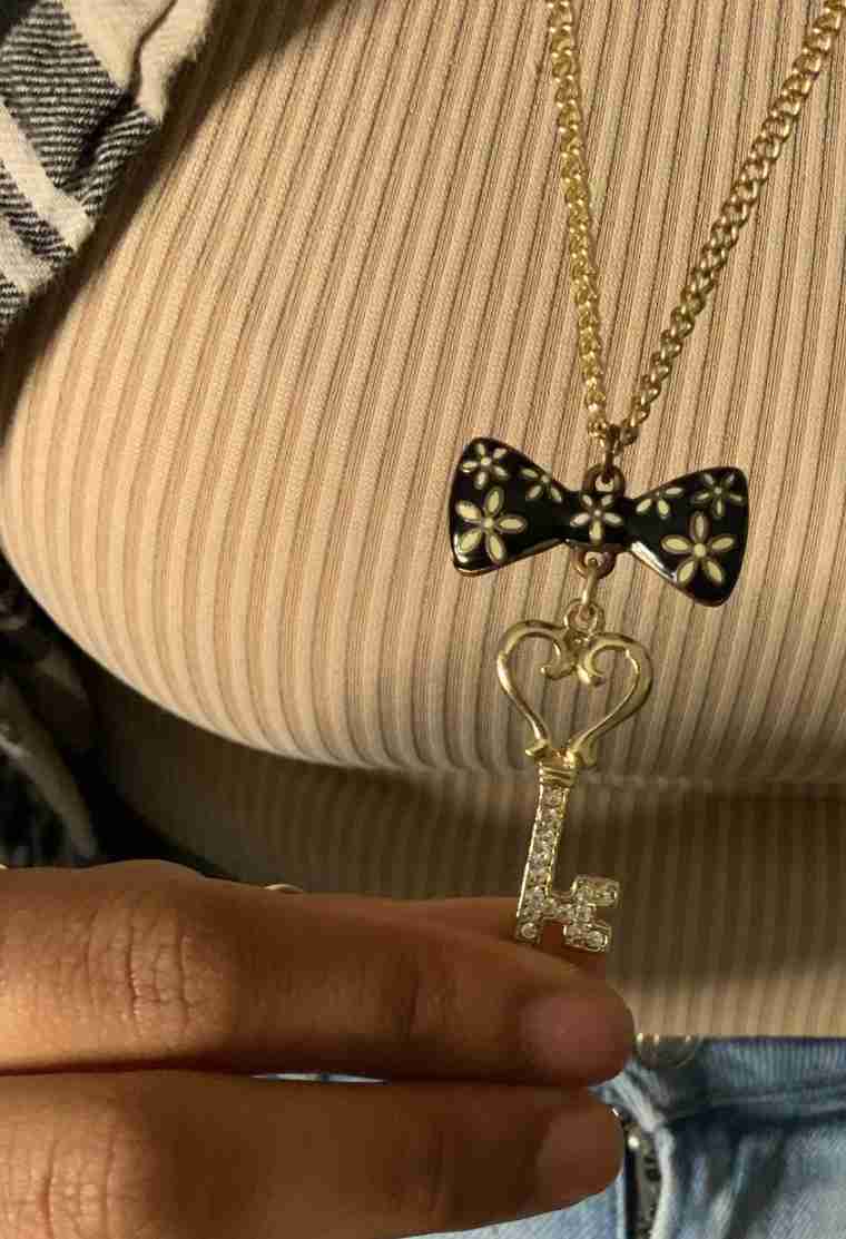 a woman wearing a sweater and a bow tie holding a key necklace.