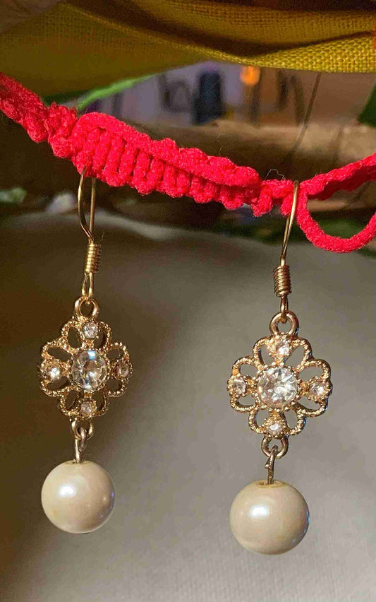 a pair of earrings hanging from a red string.