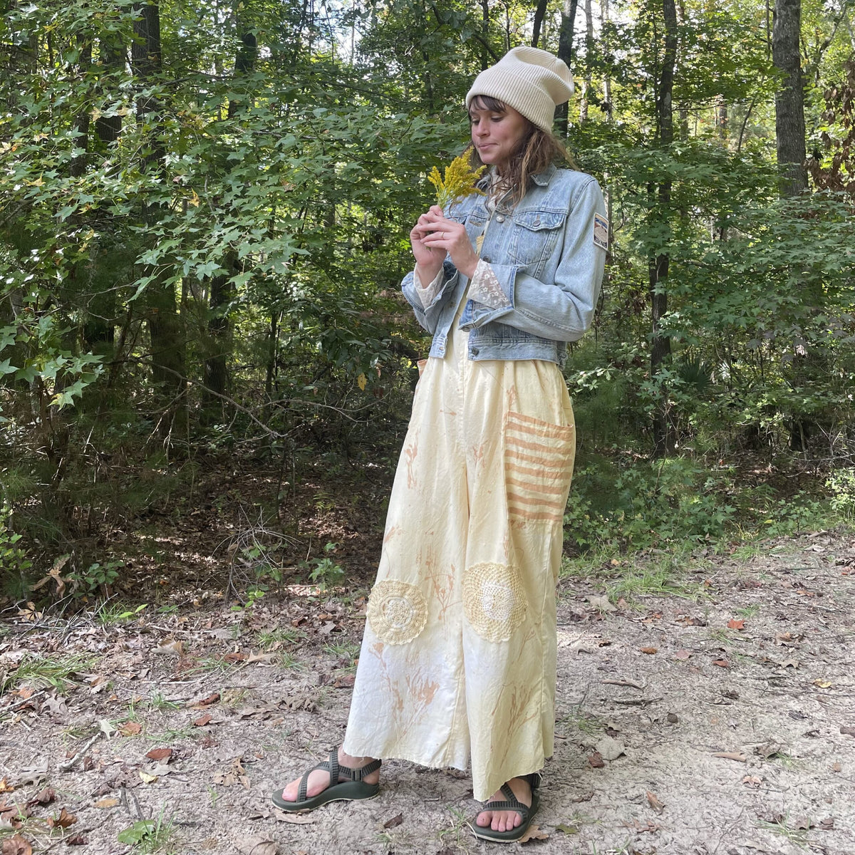 A woman in a yellow skirt standing in the woods.