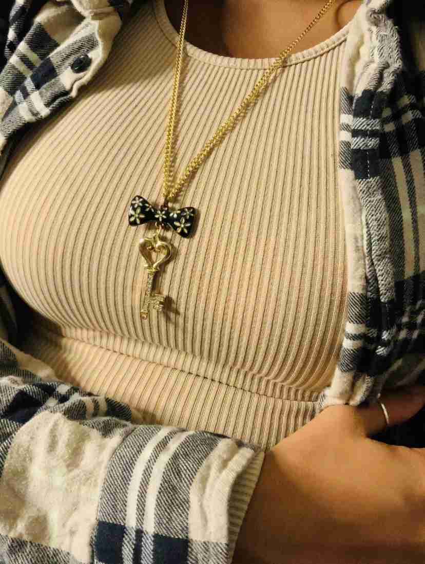 a woman wearing a plaid shirt and a bow tie necklace.
