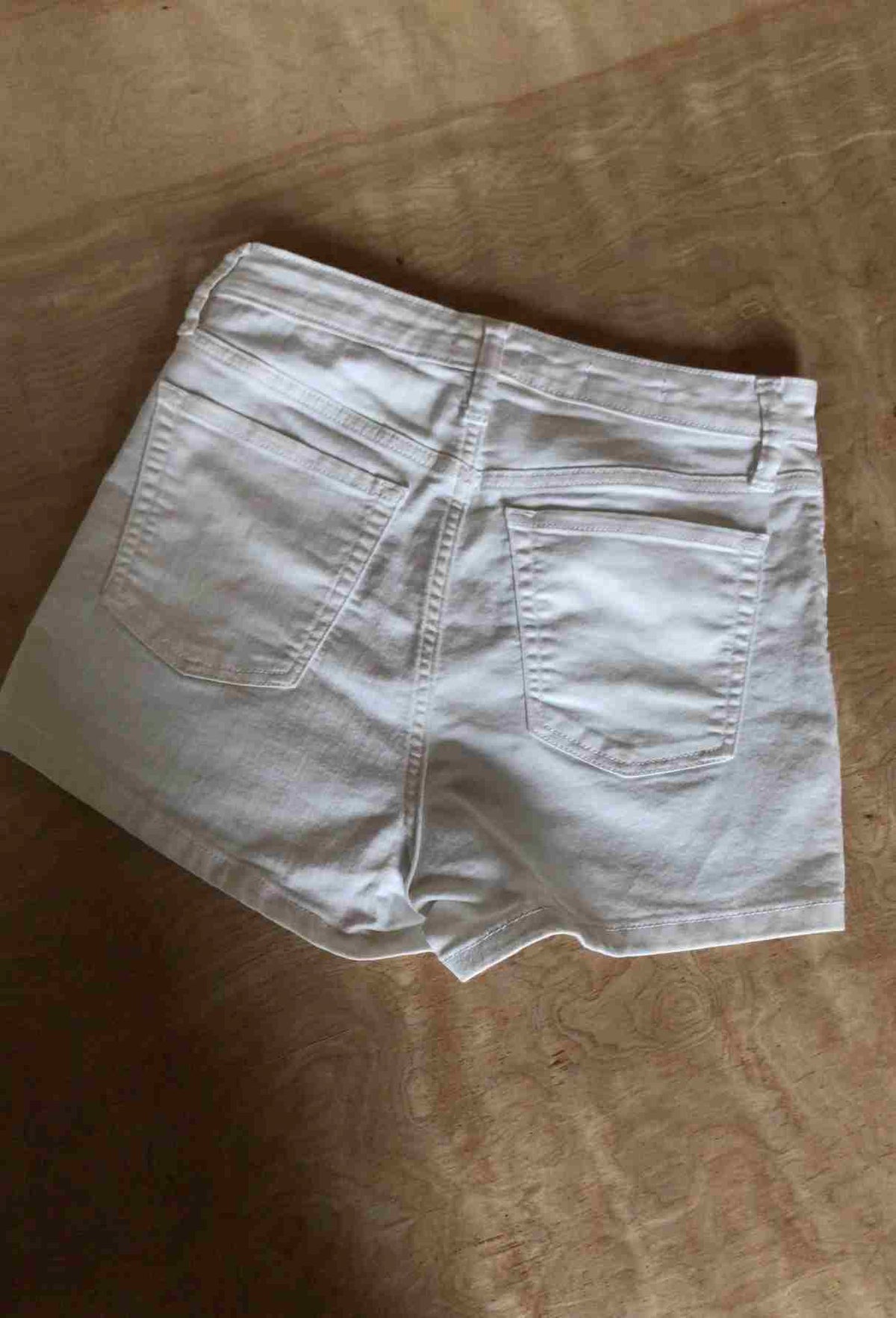 a pair of white shorts sitting on top of a bed.