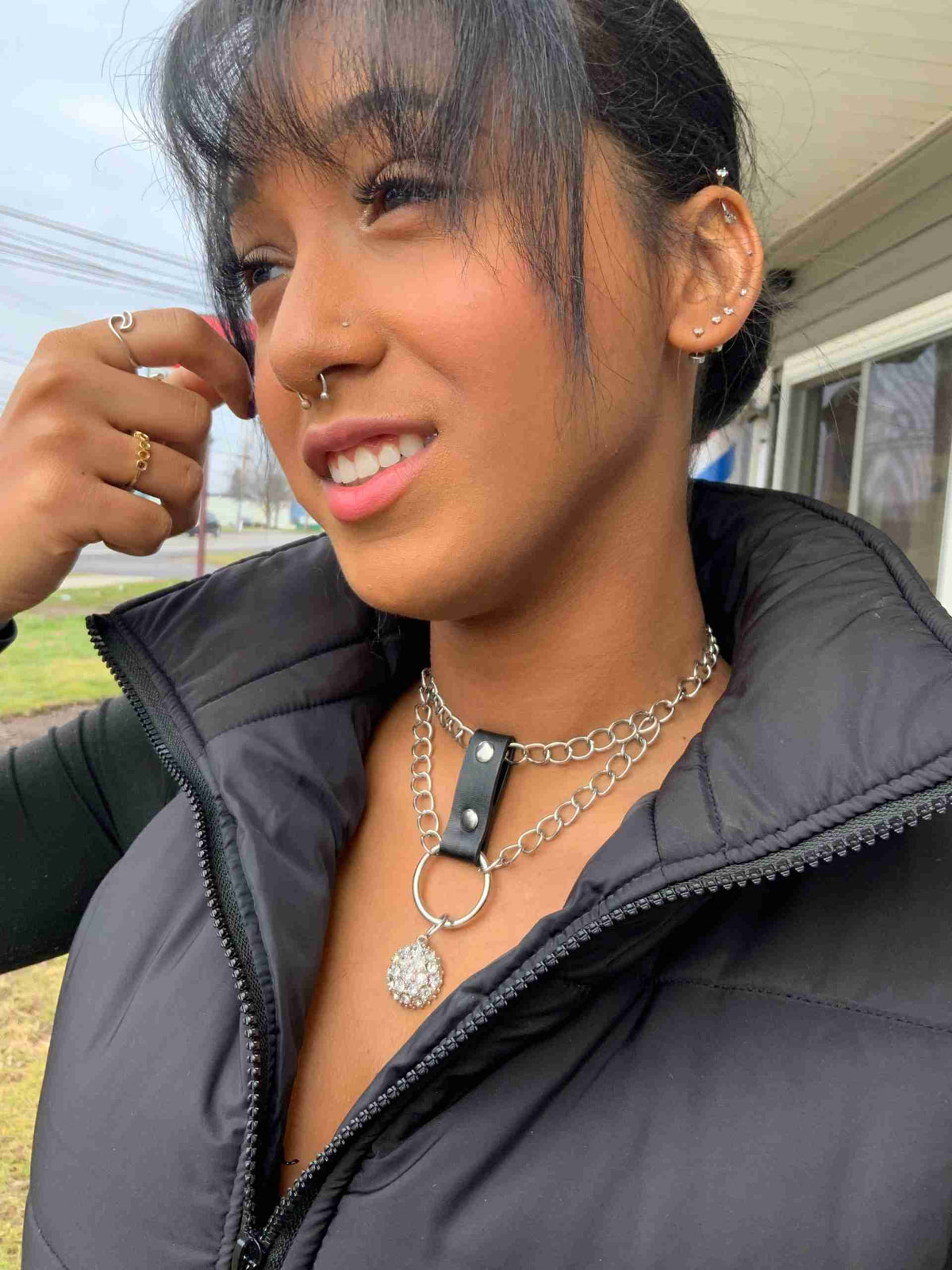 a woman wearing a black jacket and a chain around her neck.