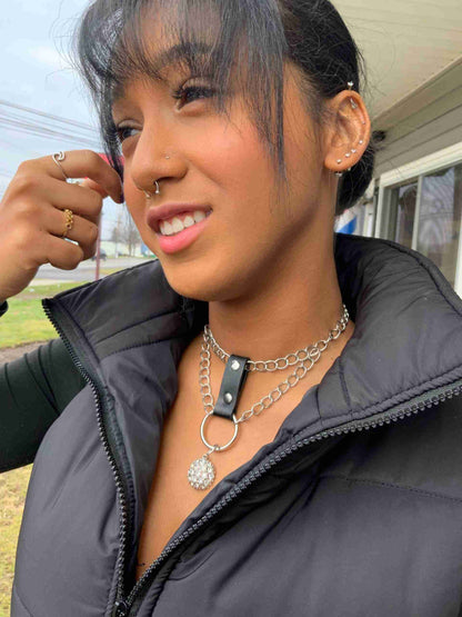 a woman wearing a black jacket and a chain around her neck.