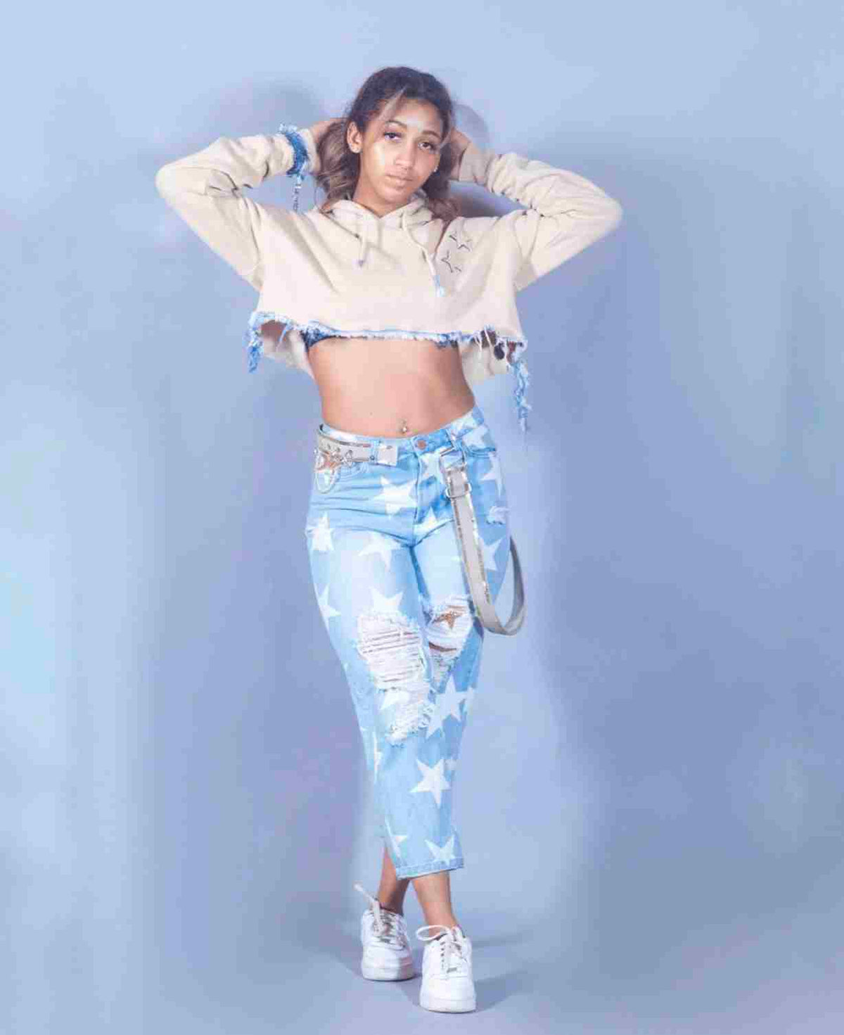 a woman wearing ripped jeans and a crop top.