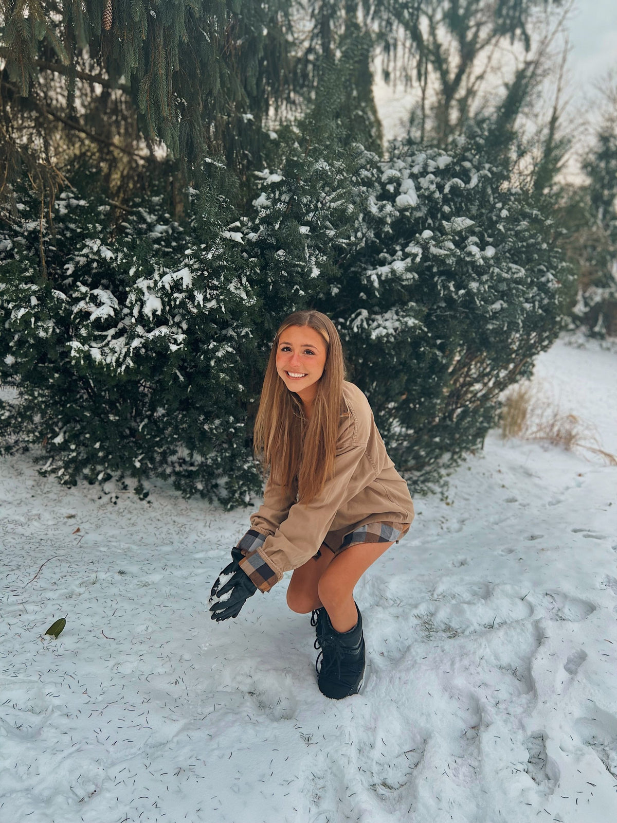 A young woman kneeling down in the Out in the Country 2pc set (Camel Flannel paired with 70s tawny earth tone stripes) in the snow.
