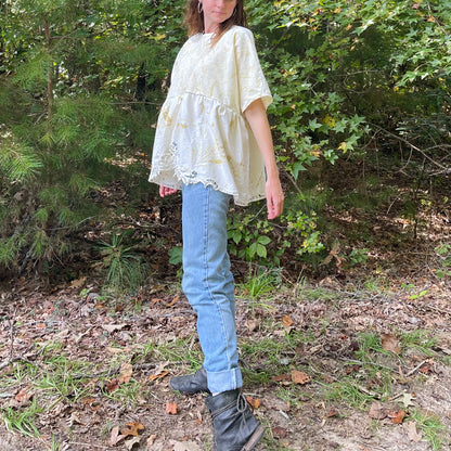 A woman in jeans and boots standing in the woods.