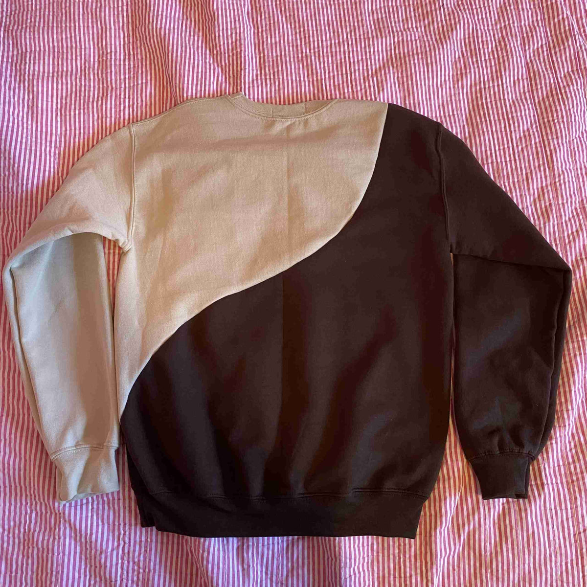 a black, white and pink sweatshirt laying on a bed.
